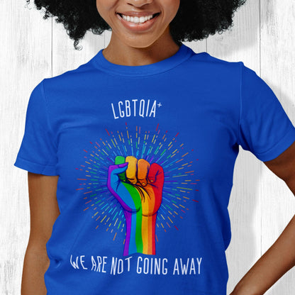 True Royal color unisex t-shirt that says, “LGBTQIA+ We Are Not Going Away” with a graphic of a rainbow fist with a rainbow-gradient color starburst behind it. Slightly arched over the starburst are the words “LGBTQIA+” and the rest of the text is below the graphic in one horizontal line.