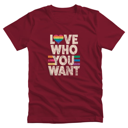 Cardinal color unisex t-shirt with a graphic that says, “Love who you want” in all caps. Each word is on its own line. The “O” in “love” is a rainbow heart.