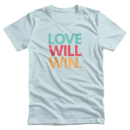 Heather Ice Blue color t-shirt with a graphic that says “Love will win.” in all caps. Each word is on its own line and is a different color. “Love” is greenish-blue, “Will” is red, and “Win.” is yellow. The graphic has a faded and slightly grungy/worn look.