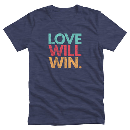 Heather Navy color t-shirt with a graphic that says “Love will win.” in all caps. Each word is on its own line and is a different color. “Love” is greenish-blue, “Will” is red, and “Win.” is yellow. The graphic has a faded and slightly grungy/worn look.