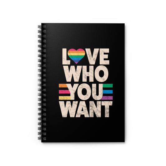 A black spiral notebook with a graphic that says, “Love who you want” in all caps. Each word is on its own line. The “O” in “love” is a rainbow heart.