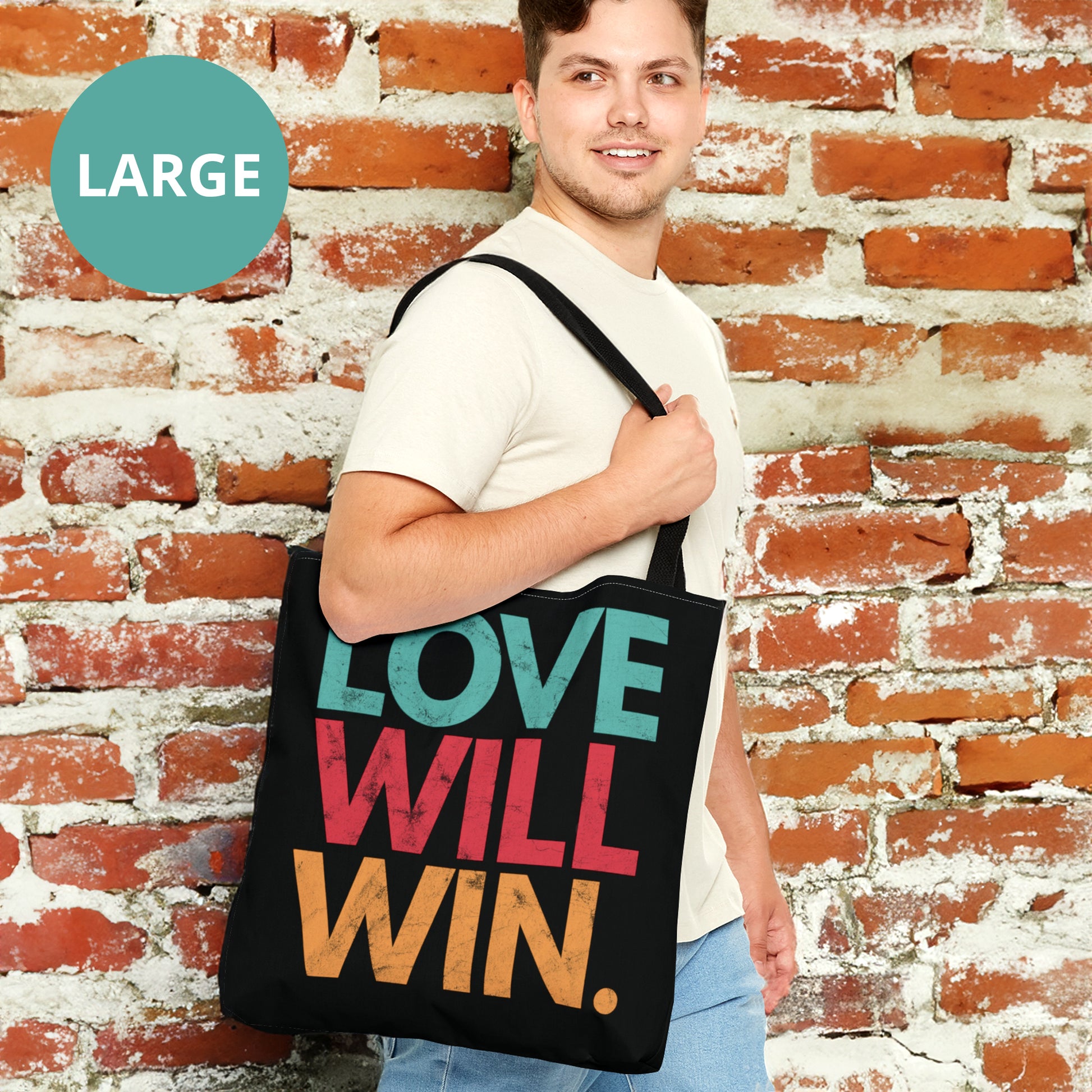 Black tote bag with a graphic that says “Love will win.” in all caps. Each word is on its own line and is a different color. “Love” is greenish-blue, “Will” is red, and “Win.” is yellow. The graphic has a faded and slightly grungy/worn look.