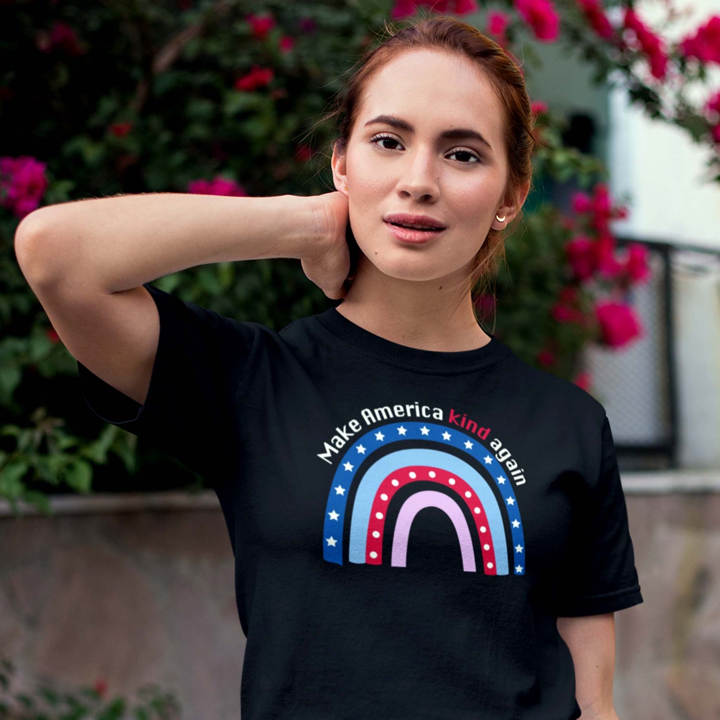 Black unisex t-shirt with a graphic of a red and blue rainbow with text arched over the top that says, “Make America Kind Again”.