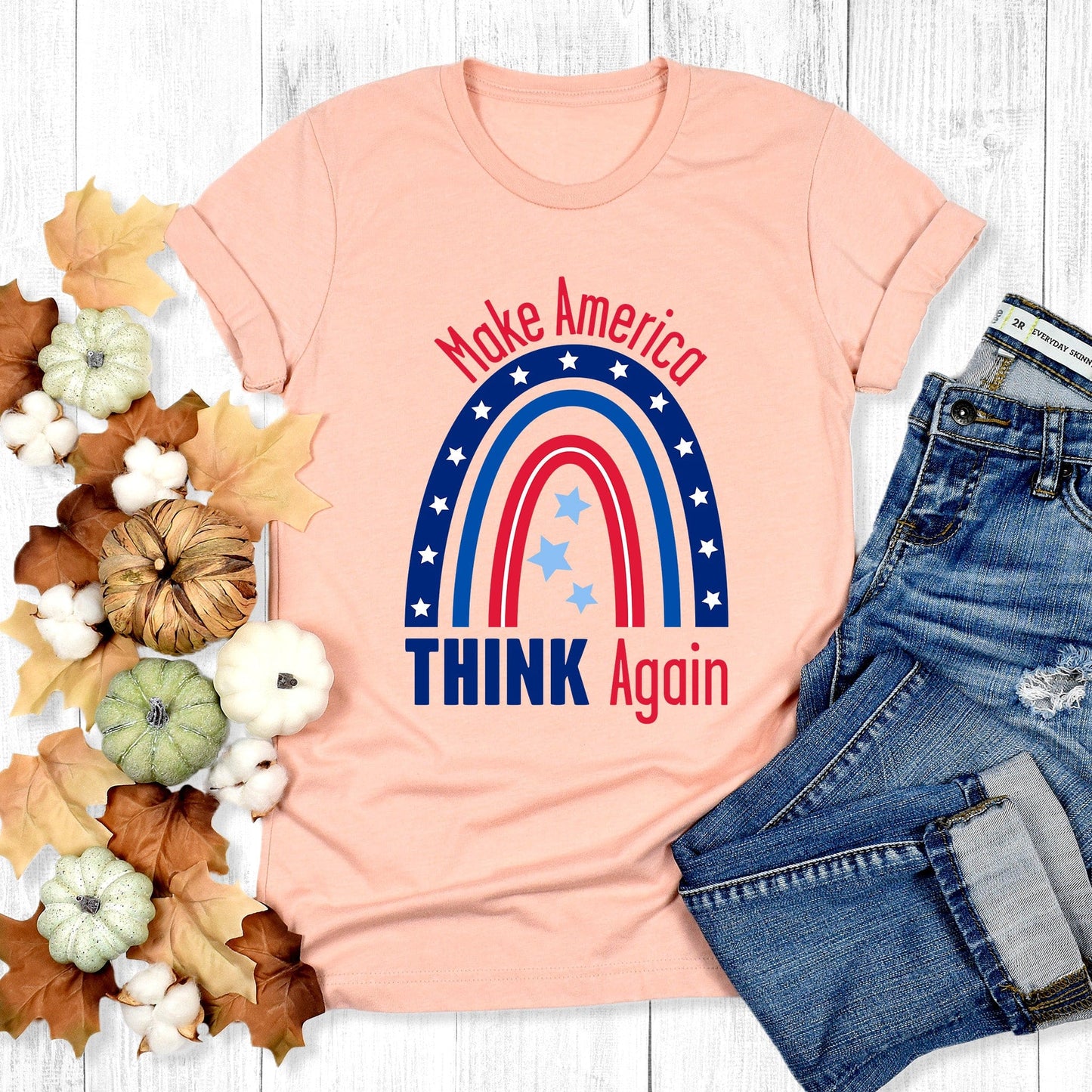 Heather Peach color unisex t-shirt that says, “Make America THINK Again” with a graphic of a blue and red rainbow. “Make America” is red and arched over the rainbow. “THINK Again” is beneath the rainbow with “THINK” being blue and “Again” being red.