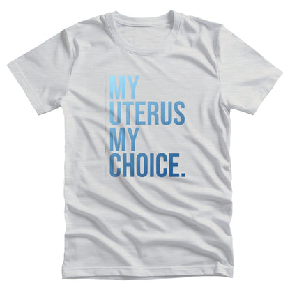 Ash color unisex t-shirt that says, “My Uterus My Choice.” The text is in a blue gradient, and each word is on its own line. There is a light, thin vertical line along the left side of the text.