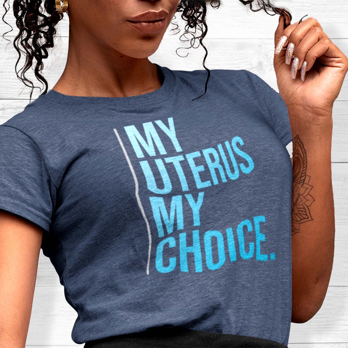 Heather Navy color unisex t-shirt that says, “My Uterus My Choice.” The text is in a blue gradient, and each word is on its own line. There is a light, thin vertical line along the left side of the text.