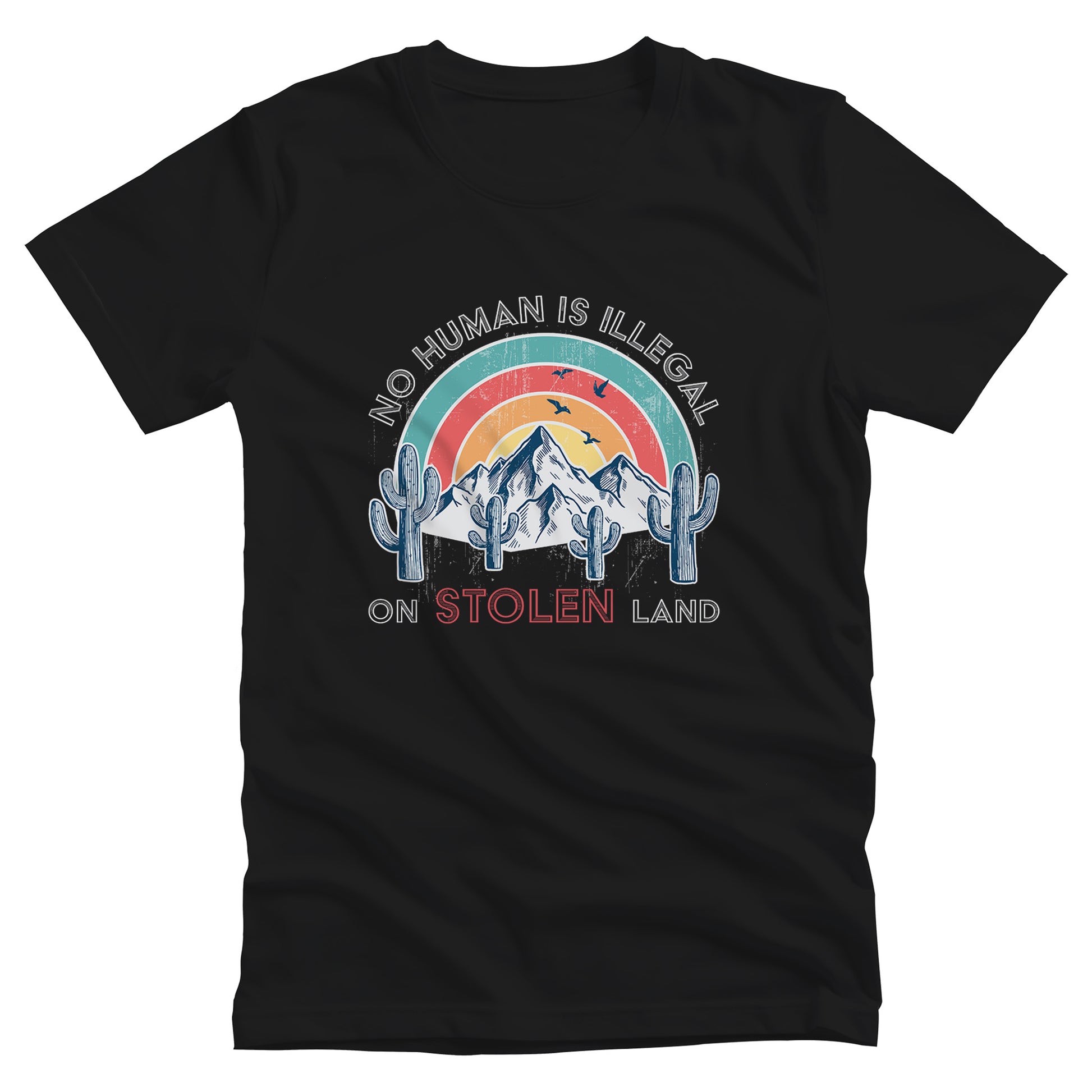 Black unisex t-shirt that says, “No Human is Illegal on Stolen Land” arched over a retro sunset with mountains and cactuses in the front. “No Human is Illegal” is arched over the top of the graphic and “on Stolen Land” is on one horizontal line beneath the graphic. The whole image is slightly distressed.