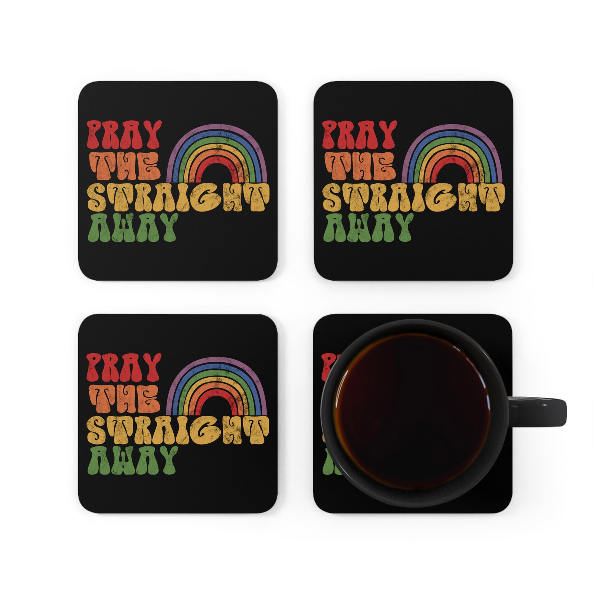 Contextual photo of four black 3.75x3.75” cork-backed coasters that say “PRAY THE STRAIGHT AWAY” in a retro font. Each word is a different retro color and on its own line. “PRAY” is maroon, “THE” is orange, “STRAIGHT” is yellow, and “AWAY” is green. The words are stacked and left-aligned with a rainbow graphic that has matching colors nestled after the word “THE” over the word “STRAIGHT.” 