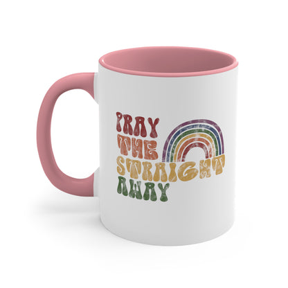 11oz ceramic mug with a pink interior and handle that says, “PRAY THE STRAIGHT AWAY” in a retro font. Each word is a different retro color and on its own line. “PRAY” is maroon, “THE” is orange, “STRAIGHT” is yellow, and “AWAY” is green. The words are stacked and left-aligned with a rainbow graphic that has matching colors nestled after the word “THE” over the word “STRAIGHT.”