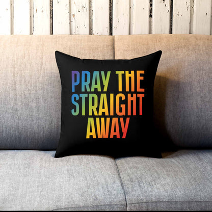 Contextual photo of a 14x14” black square decorative pillow that says, “PRAY THE STRAIGHT AWAY” in a bold font with gradient rainbow colors. The pillow is on a couch.