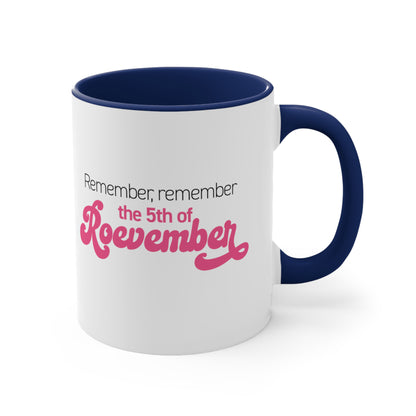 11oz ceramic mug with a navy interior and handle featuring the phrase 'Remember, Remember the 5th of Roevember'. The text 'The 5th of Roevember' is highlighted in pink, embellished with a decorative script font and additional swooshes.