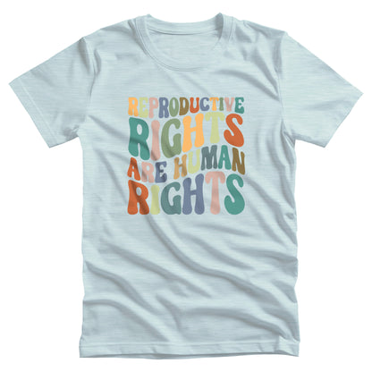 Heather Ice Blue color unisex t-shirt that says, “REPRODUCTIVE RIGHTS ARE HUMAN RIGHTS” in a retro font in a wavy shape. Each letter is a different color, and all the colors are vintage.