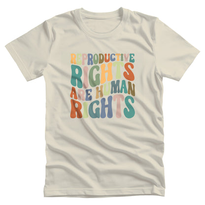 Natural color unisex t-shirt that says, “REPRODUCTIVE RIGHTS ARE HUMAN RIGHTS” in a retro font in a wavy shape. Each letter is a different color, and all the colors are vintage.