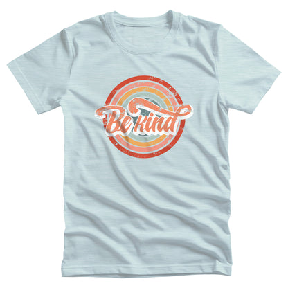 Heather Ice Blue color unisex t-shirt with a graphic that says “Be Kind.” There is a retro-colored circular rainbow behind it. The text is outlined in white and has a long swoosh that swirls from the end of the letter “d” across the entire word “kind.”