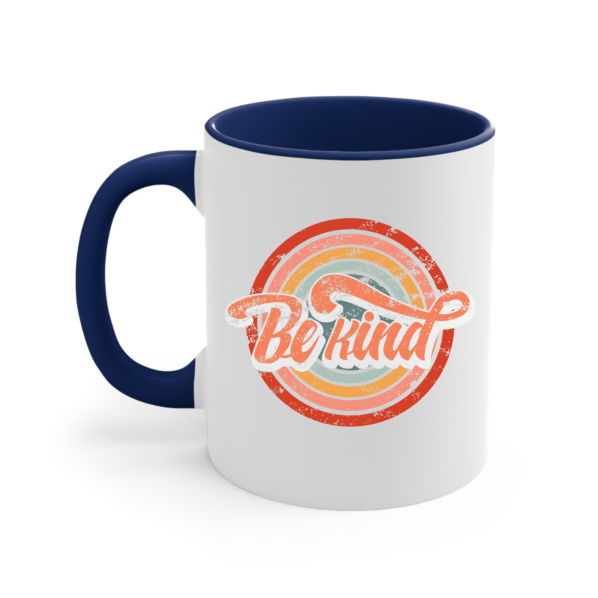 11oz white ceramic mug with a navy blue handle and interior that says “Be Kind.” There is a retro-colored circular rainbow behind it. The text is outlined in white and has a long swoosh that swirls from the end of the letter “d” across the entire word “kind.”