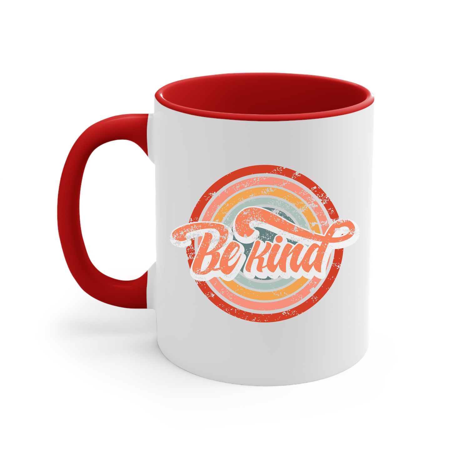 11oz white ceramic mug with a red handle and interior that says “Be Kind.” There is a retro-colored circular rainbow behind it. The text is outlined in white and has a long swoosh that swirls from the end of the letter “d” across the entire word “kind.”