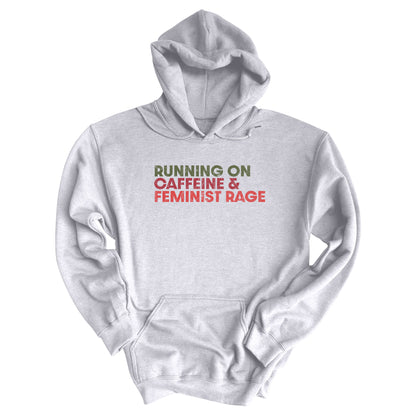 Ash color unisex t-shirt that says, “RUNNING ON CAFFEINE & FEMINIST RAGE” with each line being a different color. “RUNNING ON” is dark green, “CAFFEINE &” is dark red, and “FEMINIST RAGE” is dark orange. The text is slightly distressed.