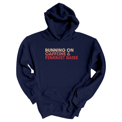 Navy color unisex t-shirt that says, “RUNNING ON CAFFEINE & FEMINIST RAGE” with each line being a different color. “RUNNING ON” is a beige color, “CAFFEINE &” is a reddish-pink color, and “FEMINIST RAGE” is red. The text is slightly distressed.