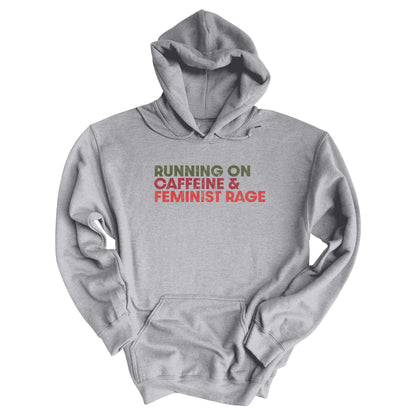 Sport Grey color unisex t-shirt that says, “RUNNING ON CAFFEINE & FEMINIST RAGE” with each line being a different color. “RUNNING ON” is dark green, “CAFFEINE &” is dark red, and “FEMINIST RAGE” is dark orange. The text is slightly distressed.