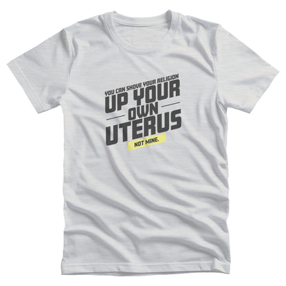 Ash color unisex t-shirt that says, “You Can Shove Your Religion Up Your Own Uterus, Not Mine.” The text is all slanted upwards, and the words “Not Mine” are in a yellow rectangle.