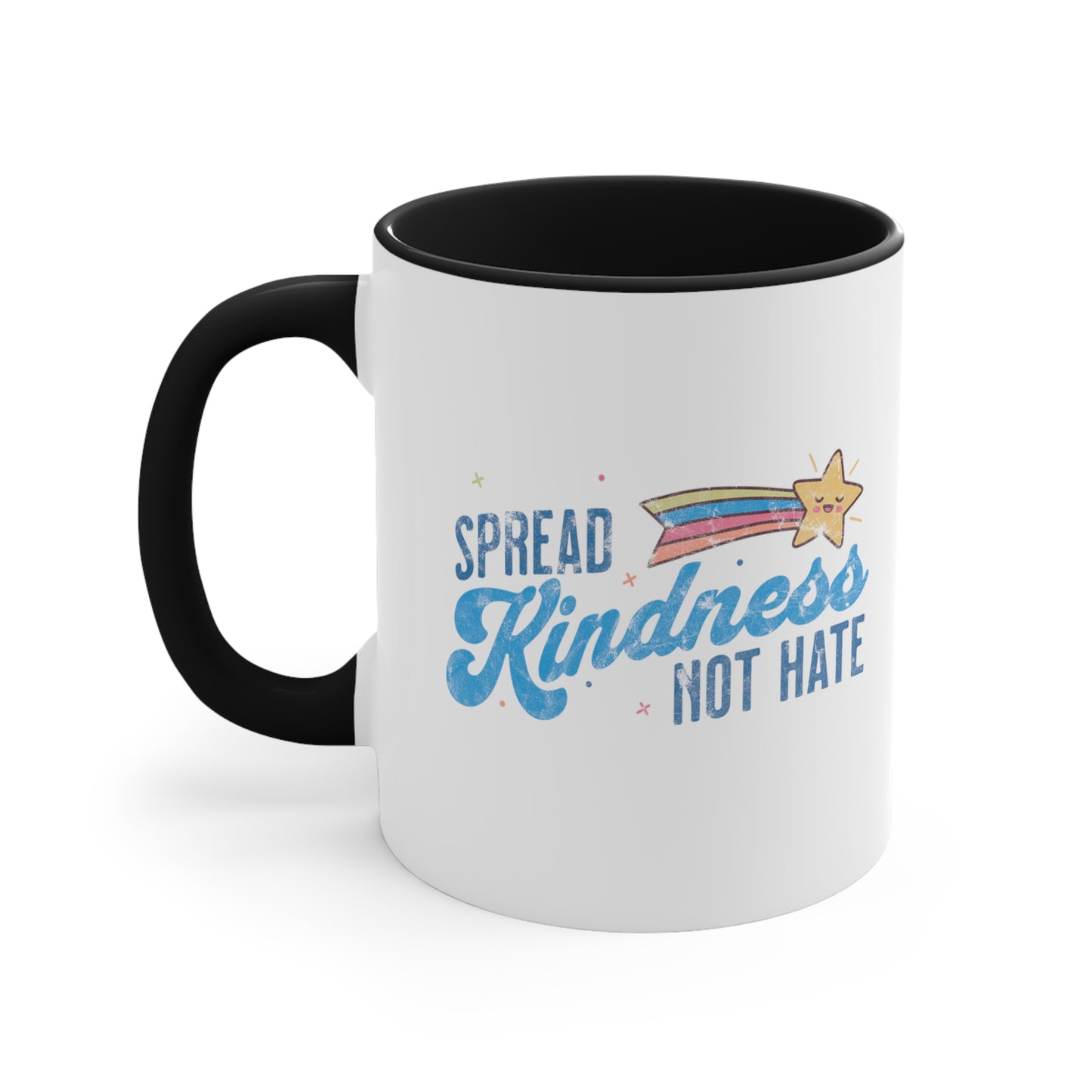 11oz ceramic mug with a black interior and handle. It has a graphic that says “Spread Kindness Not Hate” with an illustration of a rainbow shooting star over the word “kindness.” That word is in a script font, and the rest is a regular font in all caps. ”Spread” is on top of the word “Kindness” and aligned left, while “Not Hate” is below the word “kindness” and aligned to the right.