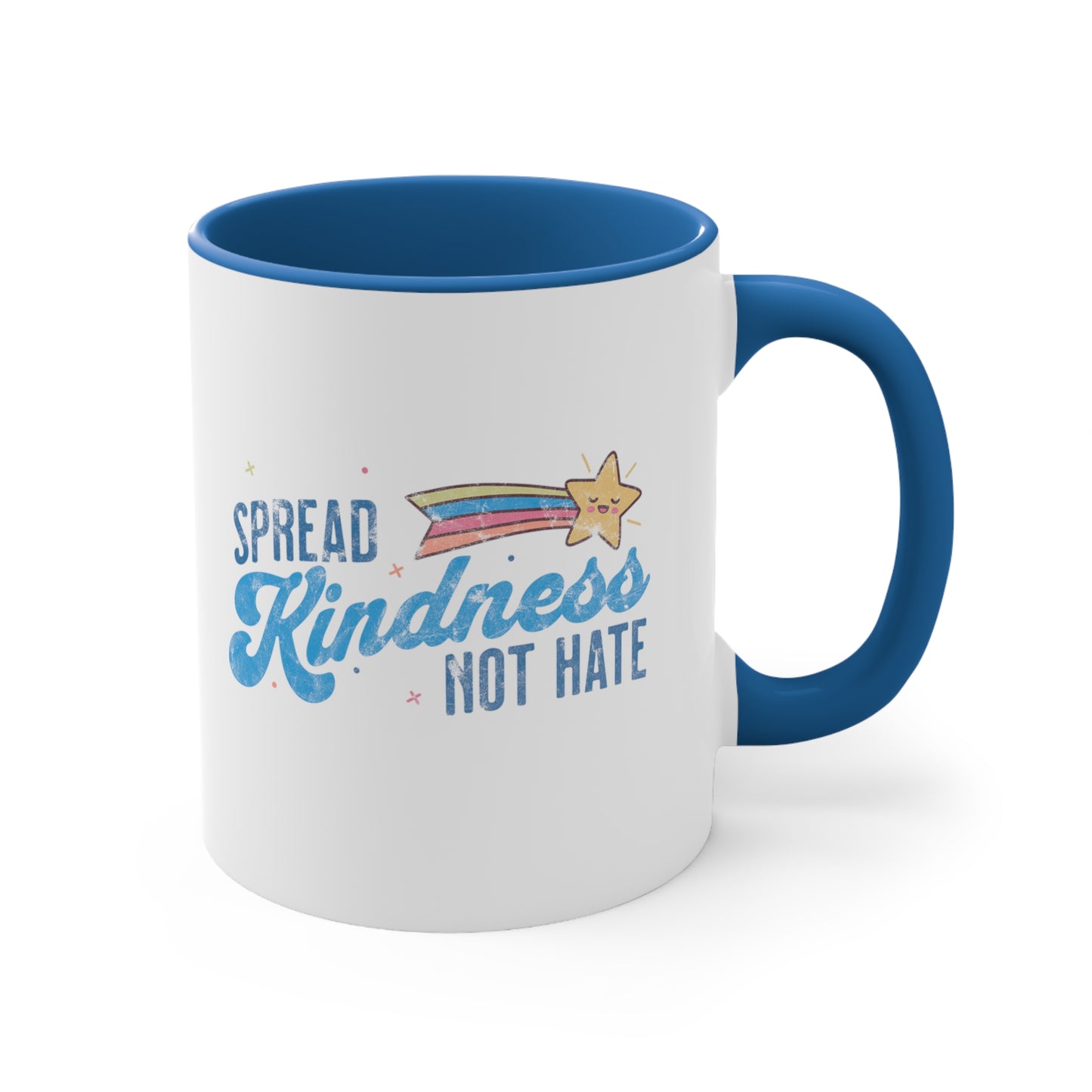 11oz ceramic mug with a blue interior and handle. It has a graphic that says “Spread Kindness Not Hate” with an illustration of a rainbow shooting star over the word “kindness.” That word is in a script font, and the rest is a regular font in all caps. ”Spread” is on top of the word “Kindness” and aligned left, while “Not Hate” is below the word “kindness” and aligned to the right.