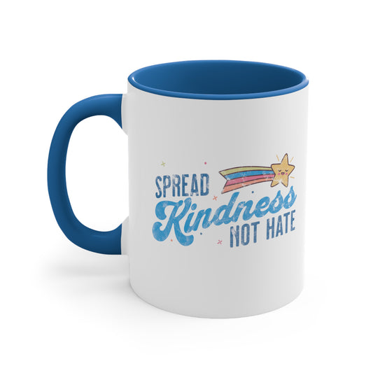 11oz ceramic mug with a blue interior and handle. It has a graphic that says “Spread Kindness Not Hate” with an illustration of a rainbow shooting star over the word “kindness.” That word is in a script font, and the rest is a regular font in all caps. ”Spread” is on top of the word “Kindness” and aligned left, while “Not Hate” is below the word “kindness” and aligned to the right.