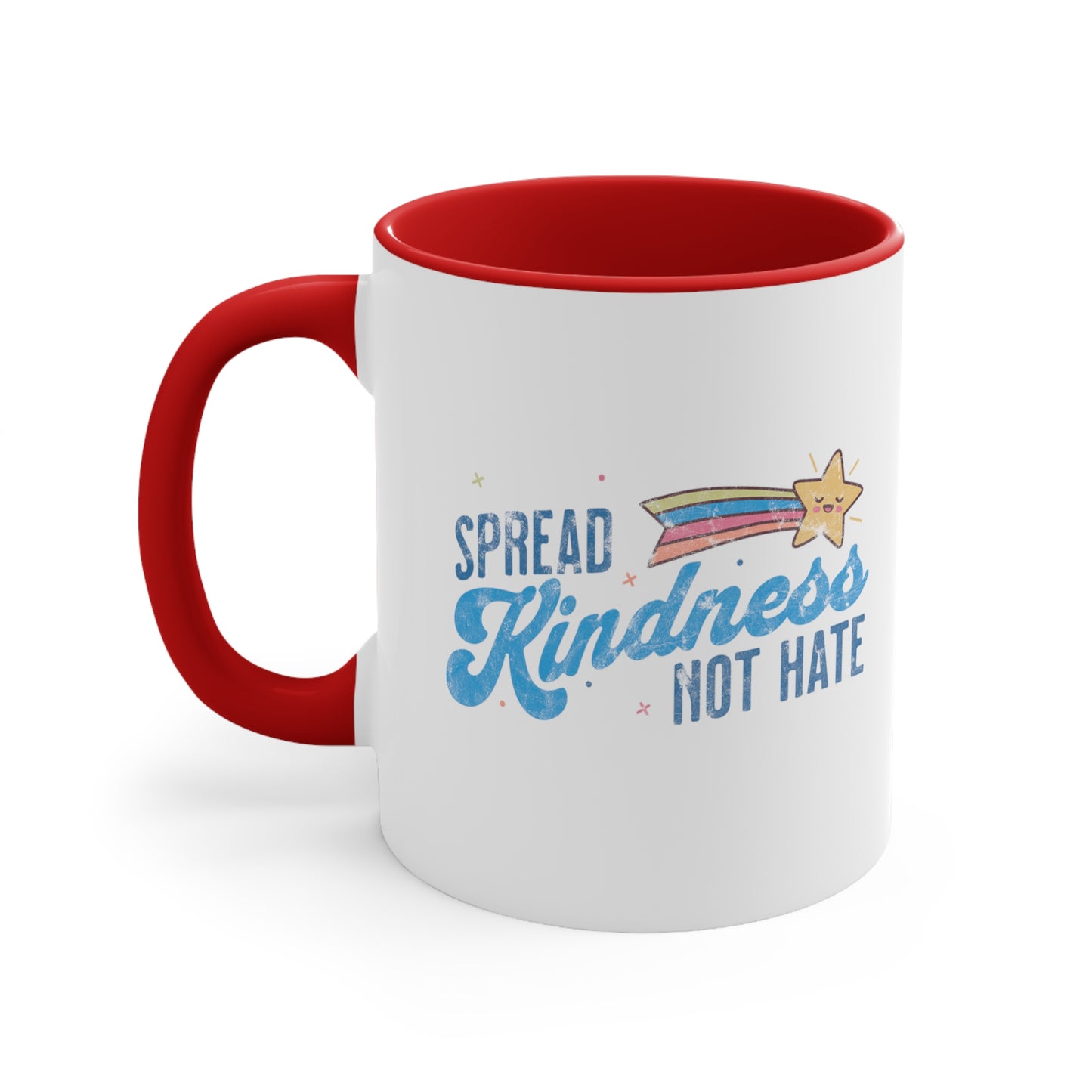 11oz ceramic mug with a red interior and handle. It has a graphic that says “Spread Kindness Not Hate” with an illustration of a rainbow shooting star over the word “kindness.” That word is in a script font, and the rest is a regular font in all caps. ”Spread” is on top of the word “Kindness” and aligned left, while “Not Hate” is below the word “kindness” and aligned to the right.