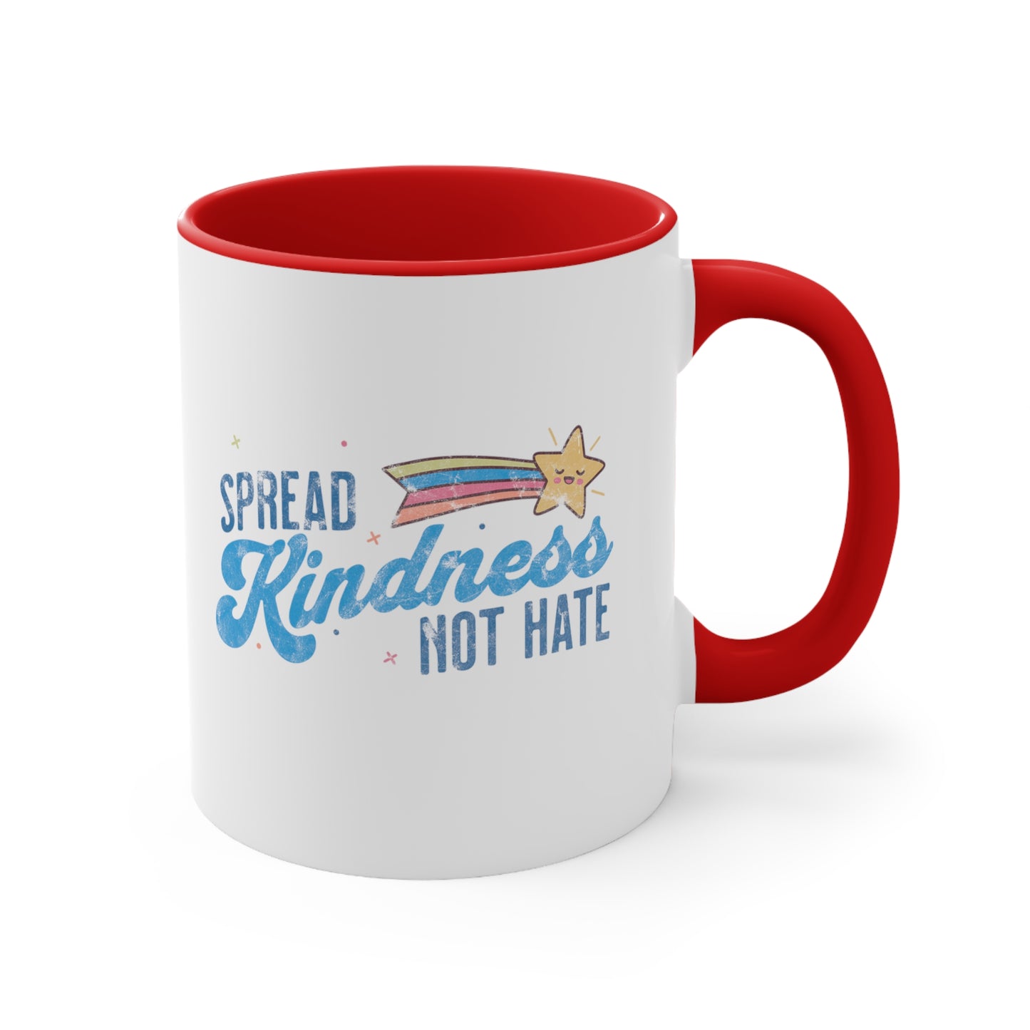 11oz ceramic mug with a red interior and handle. It has a graphic that says “Spread Kindness Not Hate” with an illustration of a rainbow shooting star over the word “kindness.” That word is in a script font, and the rest is a regular font in all caps. ”Spread” is on top of the word “Kindness” and aligned left, while “Not Hate” is below the word “kindness” and aligned to the right.