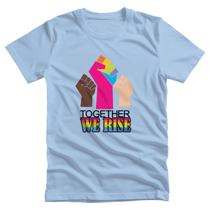 Baby Blue color unisex t-shirt with a graphic a brown skin-colored fist on the left, a rainbow fist front and center, and a white skin-colored fist on the right. Below that reads “Together We Rise.” “Together” is on one line and “We Rise” is below that in rainbow colors.