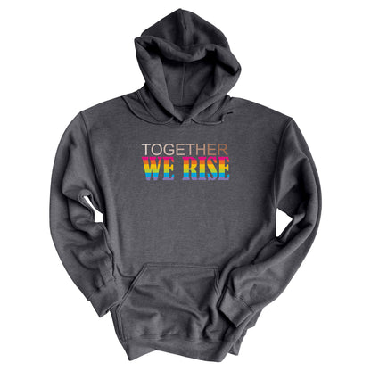 Dark Heather color unisex hoodie with a graphic that says “Together We Rise”. The word “Together” is a skin-colored gradient that spans from light to dark. “We Rise” is in all caps and horizontal rainbow stripes.