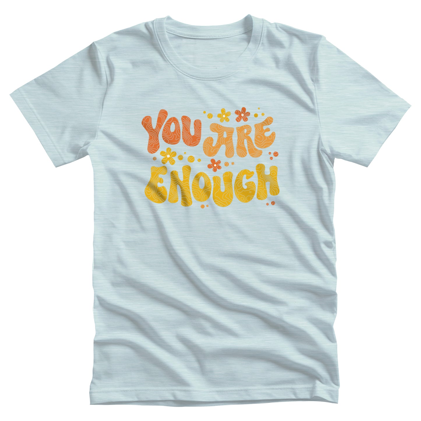 Heather Ice Blue color unisex t-shirt with a graphic that says “You Are Enough” in a retro font. There are small retro flowers spaced throughout. “You” is reddish-orange, “Are” is orange, and “Enough” is yellow, all retro as well.