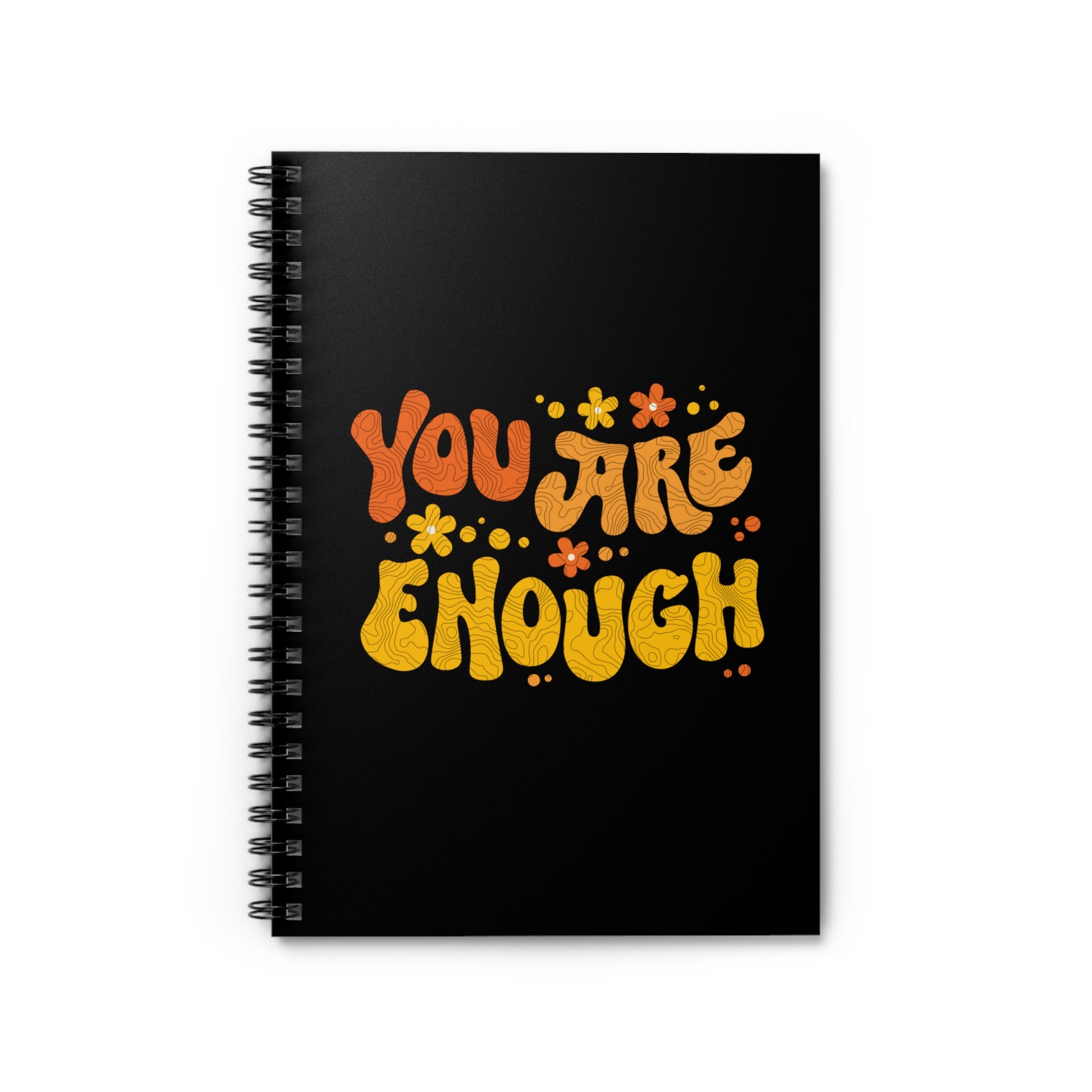 A black spiral-bound notebook with a graphic on the front that says “You Are Enough” in a retro font. There are small retro flowers spaced throughout. “You” is reddish-orange, “Are” is orange, and “Enough” is yellow, all retro as well.